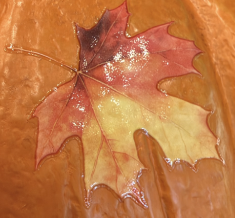 Close-up of shiny gloss fall leaf stickers on a white pumpkin