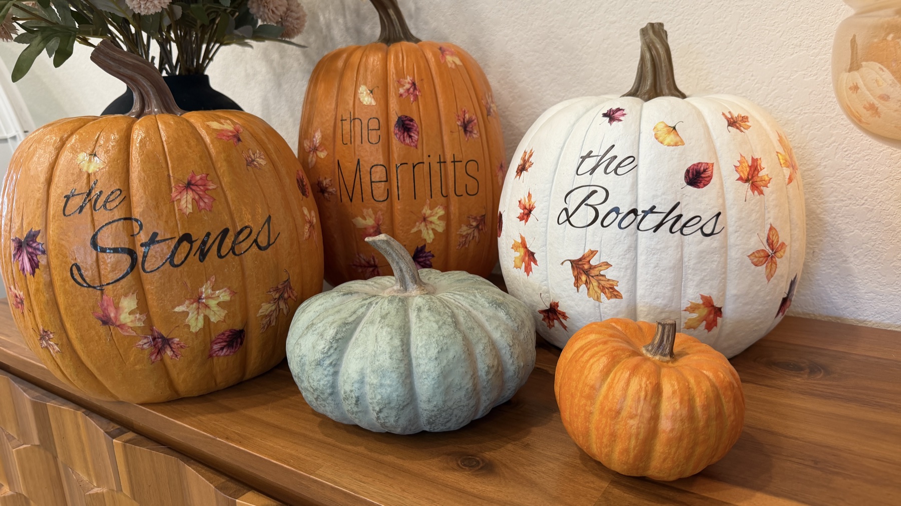 Three plastic pumpkins decorated with the Stones, Merritts, and Boothes family names and autumn leaf stickers